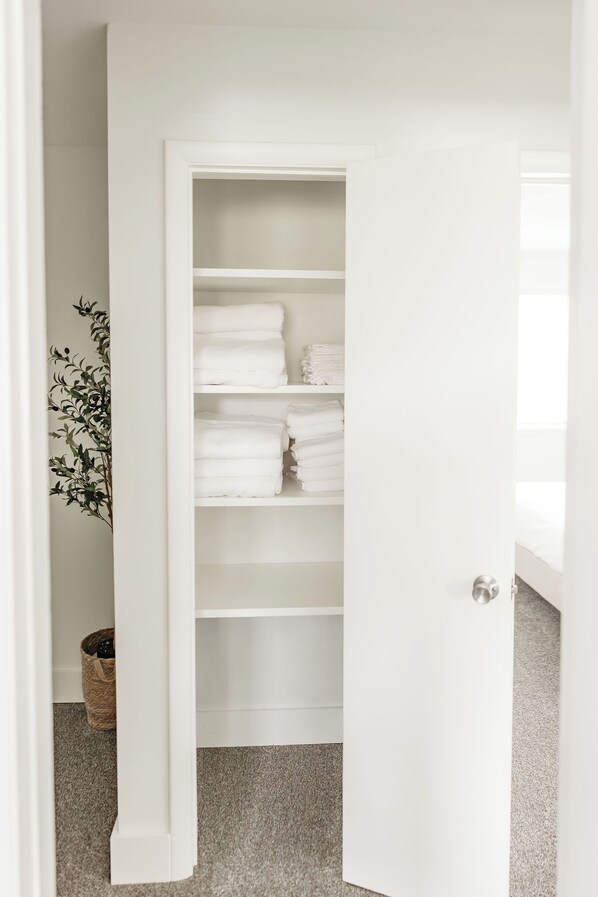 A white closet with shelves holding folded towels.