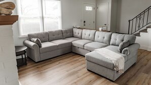 Ein modernes Wohnzimmer mit einem Ecksofa, einem kleinen runden Tisch und einer Treppe.
