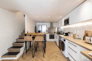 A modern kitchen with a wooden staircase, built-in appliances, and a bar area. - Duplex Apartment With Pool a/c 2br/4p - Cannes (Cannes)