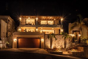 Ein zweistöckiges Haus mit Garage, Steinmauer und einem Balkon mit Pflanzen.