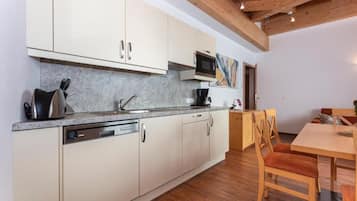 A modern kitchen with a dishwasher, microwave, and wooden dining table with chairs.