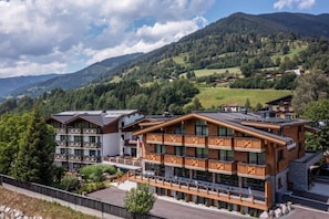 Un hotel de varios pisos con balcones, con montañas al fondo.