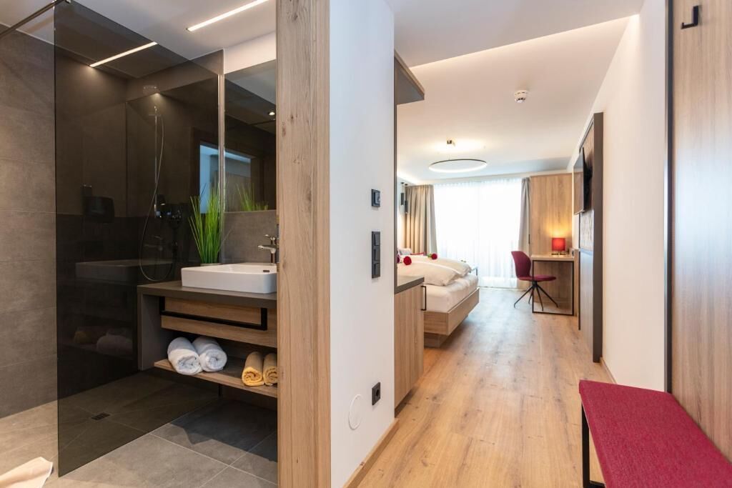 A modern bathroom with a shower, sink, and towel storage.
