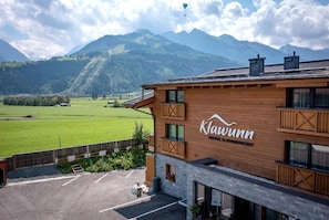 Un edificio de madera con la señalización 'Klawunn', un estacionamiento y un paisaje montañoso al fondo.