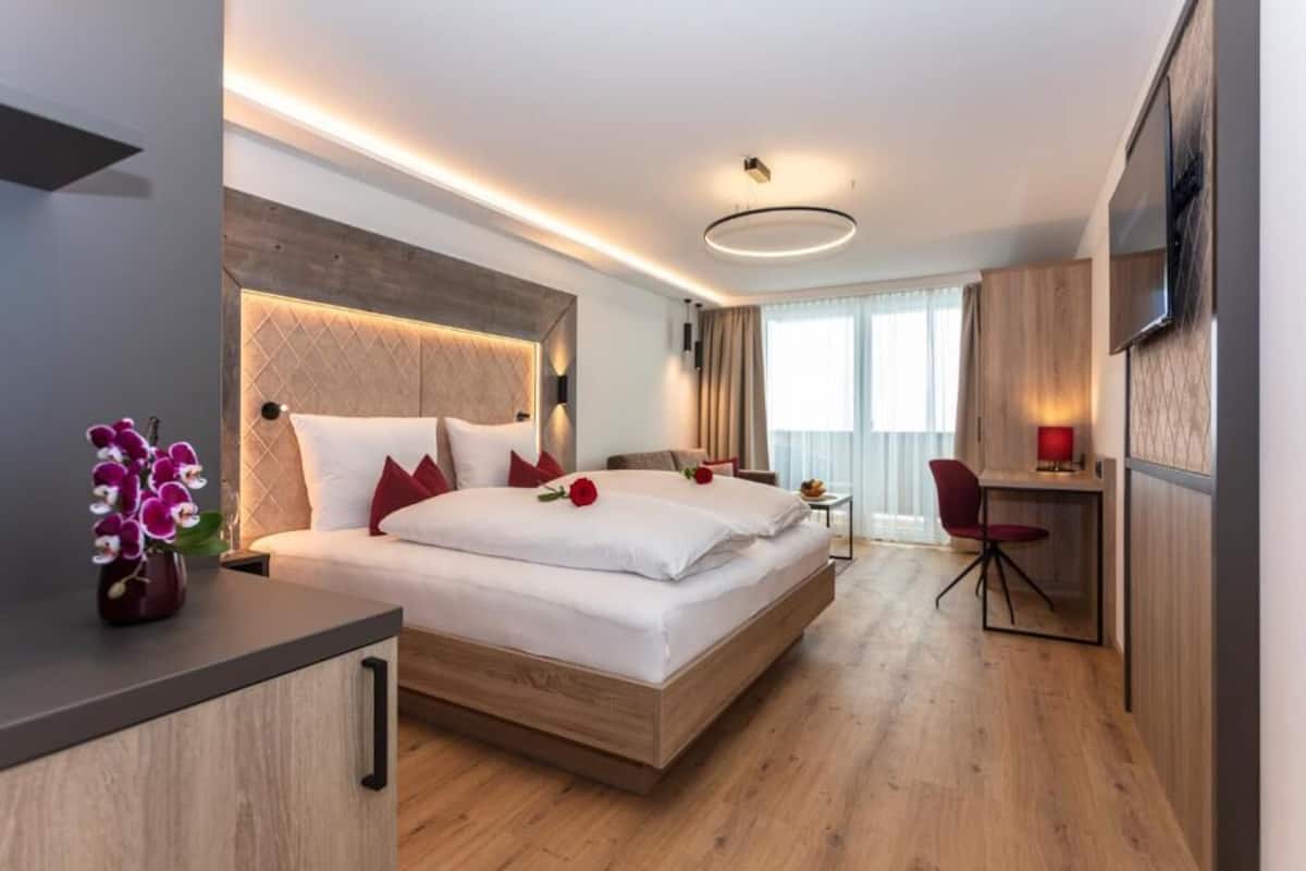 Una habitación de hotel moderna con una cama grande, un escritorio y una silla.