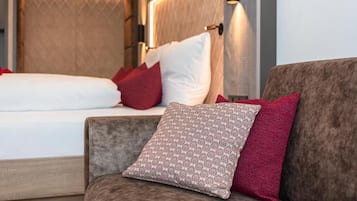 Habitación de hotel con cama, sofá, almohadas estampadas y una lámpara fijada a la pared.