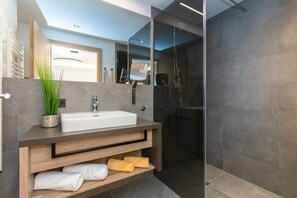 Un baño moderno con un lavamanos integrado, cabina de ducha de vidrio y tocador de madera.
