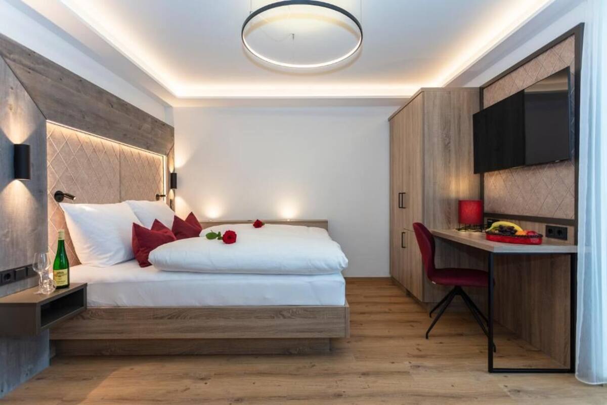 Un dormitorio moderno con cama, mesita de noche y un escritorio empotrado con silla.