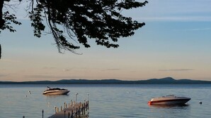 Un lago tranquilo con dos barcos amarrados en un muelle que se adentra en el agua.