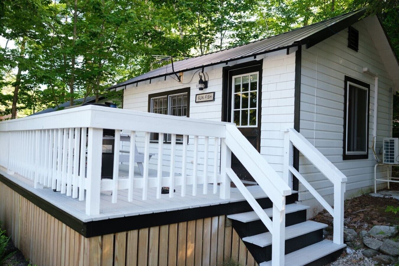 Un bâtiment blanc doté d’une terrasse et d’un escalier menant à une porte sur laquelle est inscrit « SUN FISH ».