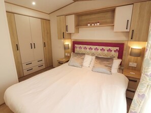 Ein Schlafzimmer mit einem großen Bett, einem Holzschrank, Nachttischen und einem Kopfteil mit Blumenmuster.
