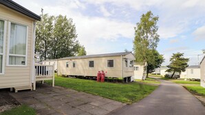 A row of mobile homes with a paved driveway and grassy areas. - Daletree View (Skipton)