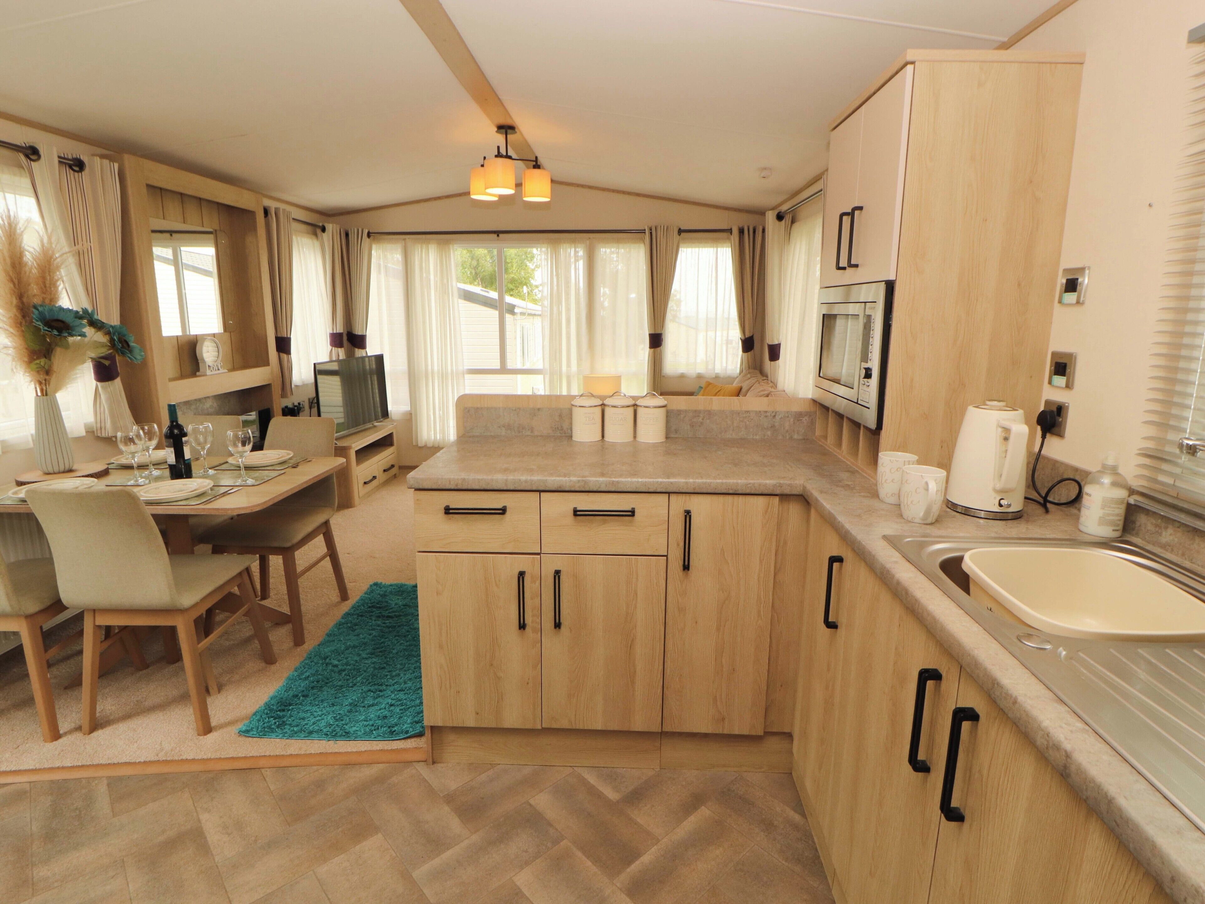 A compact kitchen with wooden cabinets, a microwave, a coffee maker, and a sink.