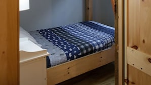 Ein Schlafzimmer mit Etagenbetten, einem Fenster, einem kleinen Schreibtisch und einer Deckenleuchte.