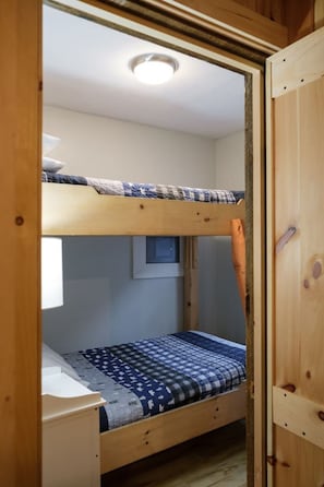Habitació amb literes, una finestra, un escriptori petit i una làmpada al sostre.