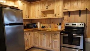 Eine Küche mit Holzschränken, einem Edelstahlkühlschrank, einer Mikrowelle, einem Spülbecken und einem Doppelbackofen.