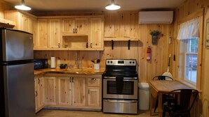Eine Küche mit Holzschränken, einem Edelstahlkühlschrank, einer Mikrowelle, einem Backofen und einem Spülbecken.