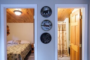 Ein Schlafzimmer mit einem Bett, einer Holzbalkendecke und einer Wand mit drei runden Wandbildern.