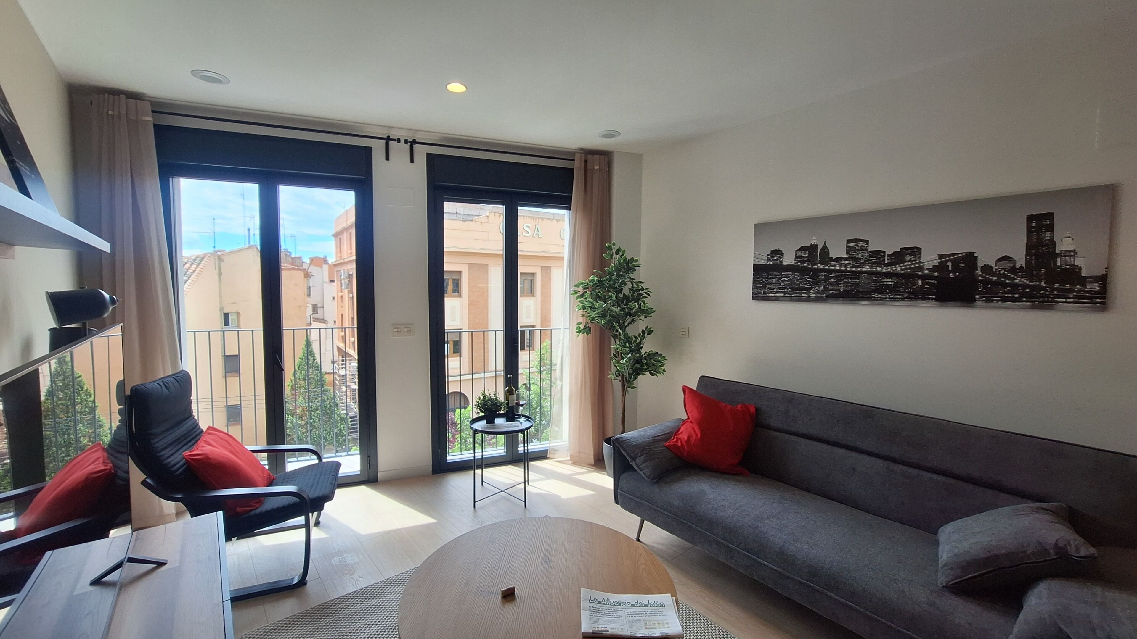 A modern living room with a sofa, a chair, a coffee table, and a cityscape painting on the wall.
