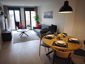 A modern living room with a dining area, a sofa, a coffee table, and a cityscape painting on the wall. - Apartamentos Plaza Costa 7 (Calatayud)