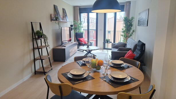 Un comedor moderno con una mesa redonda, sillas y vistas de la ciudad a través de amplios ventanales.