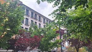 A multi-story building with balconies, surrounded by trees with green and red leaves. - Apartamentos Plaza Costa 7 (Calatayud)