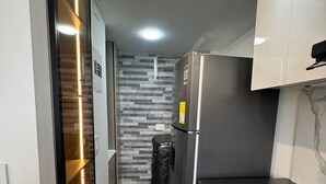 Eine schmale Küche mit Kühlschrank, Mikrowelle und Herd.