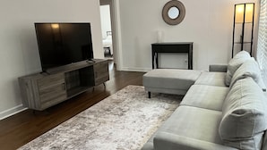 Ein Wohnzimmer mit Fernseher, Sofa, Teppich und einem kleinen Tisch.