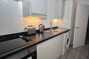 A modern kitchen with a built-in washing machine, a toaster, and a kettle. - Contemporary 1 Bedroom Apartment in Leeds (Leeds)