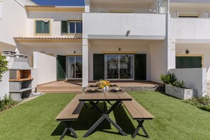 A patio with a table set for four, a barbecue grill, and a small garden area. - #375 Spacious Townhouse with Pool, BBQ, and Parking (Albufeira)