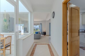 A modern apartment with a dining area, a living room with a sofa, a kitchen, and a large window. - #375 Spacious Townhouse with Pool, BBQ, and Parking (Albufeira)