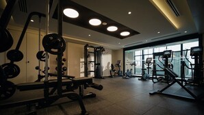 Un gimnasio con equipo de levantamiento de pesas, máquinas de cardio y amplias ventanas.