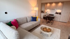 A modern living room with a grey sofa, a white rug, and a dining area with a table and chairs. - New Executive Condo Midtown Toronto -  Airport pick up included - Free Parking (Toronto)