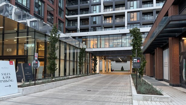 A modern building with glass facades, a sign for sales and parking, and a loading bay sign. - New Executive Condo Midtown Toronto -  Airport pick up included - Free Parking (Toronto)