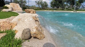 Una piscina con agua cristalina, rodeada de rocas y follaje.
