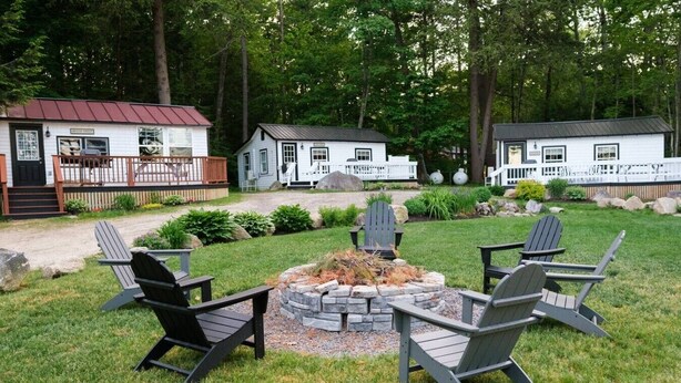 A cabin with a deck, a fire pit with chairs, and a well-maintained lawn. - Lake Trout Cottage on the Stunning West Shore of Sebago Lake (Sebago)