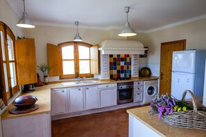 Una cocina con armarios blancos, estufa, fregadero y refrigerador.