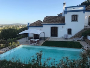 A house with a swimming pool, outdoor seating, and a view of the countryside.