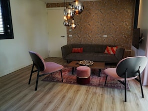 Ein Wohnzimmer mit einer Couch, zwei Sesseln, einem Couchtisch und einer Wand mit Muster.