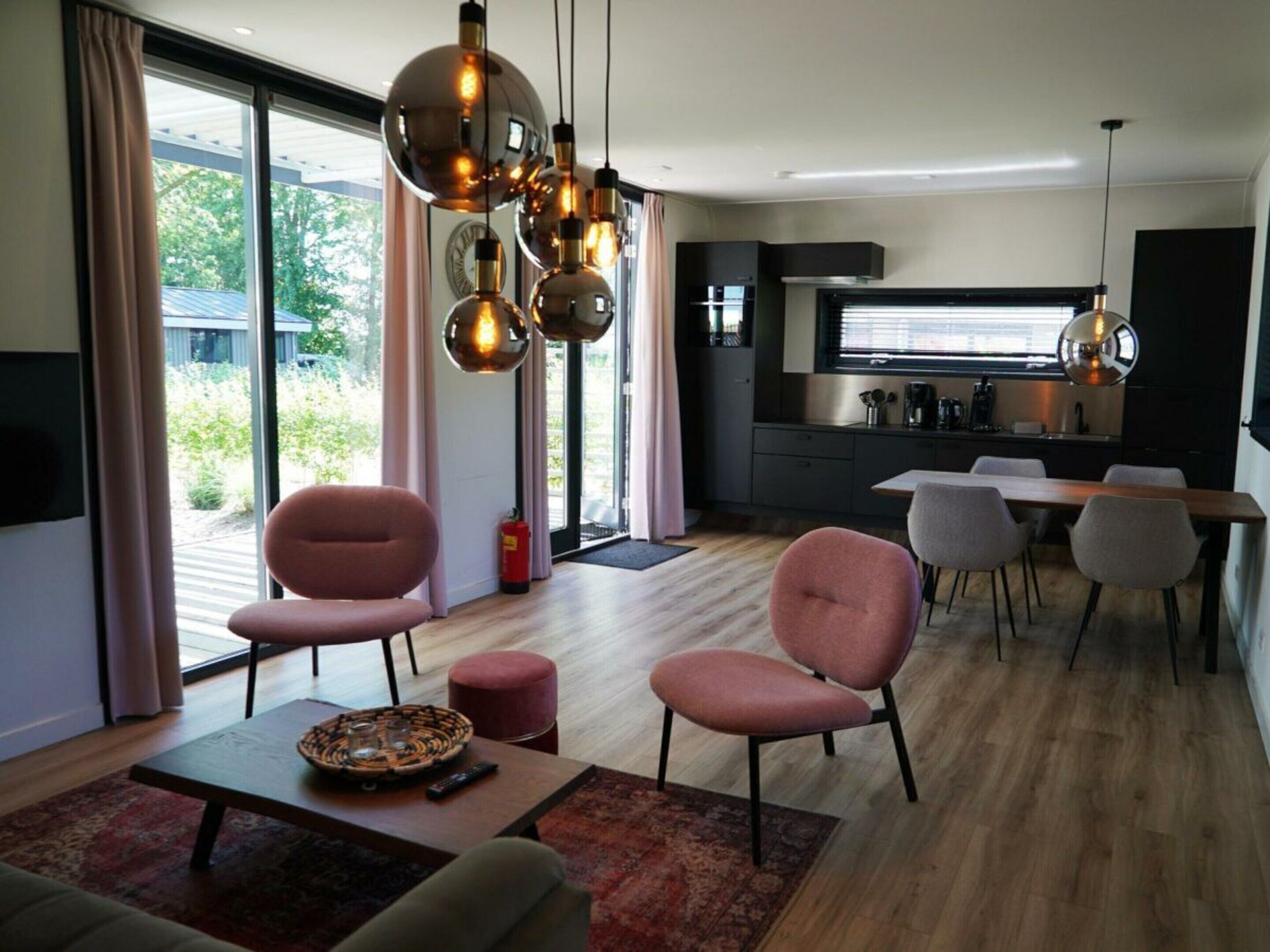 A modern living room with a sofa, chairs, a dining table, and a kitchen in the background.