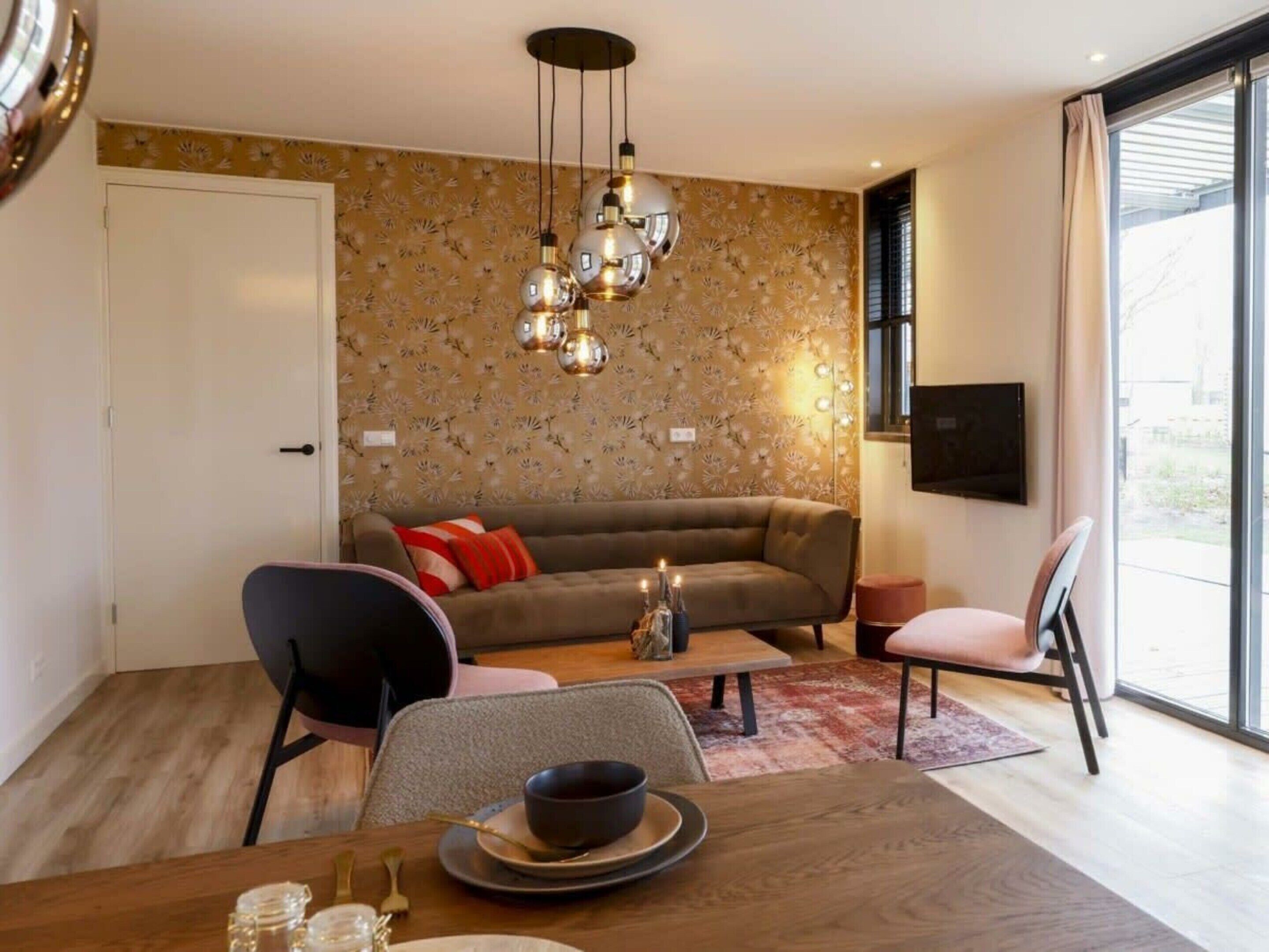 Una sala de estar moderna con sofá, sillas, una mesa de comedor y una lámpara decorativa.