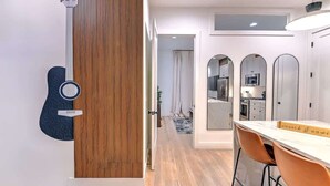 Une cuisine moderne avec des meubles blancs, un mur d’accent en bois et un coin repas comprenant une table et des chaises.