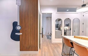 Eine moderne Küche mit weißen Schränken, einer Wand als Holzvertäfelung und einem Essbereich mit Tisch und Stühlen.