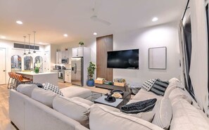 Ein modernes Wohnzimmer mit einer Couch, einem Couchtisch und einem Flachbildfernseher.