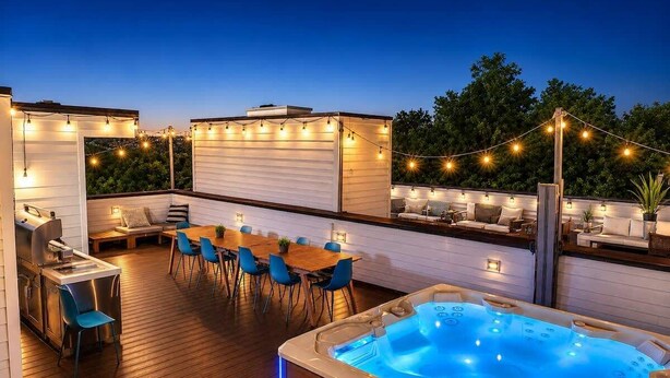 Une terrasse sur le toit avec un jacuzzi, des sièges d’extérieur et des guirlandes lumineuses.