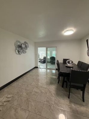 A spacious room with a dining area, a glass door leading outside, and a ceiling light. - Anihouse . (Las Vegas)