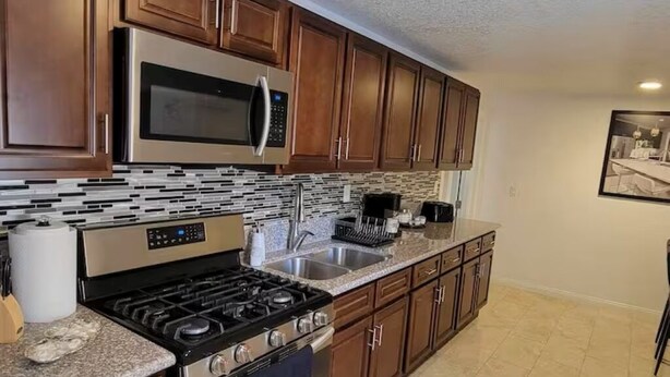 A kitchen with wooden cabinets, stainless steel appliances, a tiled floor, and a framed picture on the wall. - Ani place  . (Las Vegas)