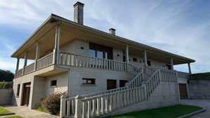 En toetagers bygning med balkon, trappe og en velholdt græsplæne.