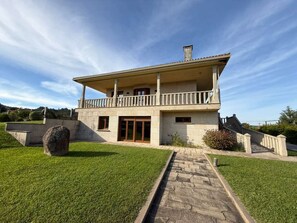 A two-story building with a balcony, a stone pathway, and a grassy lawn.