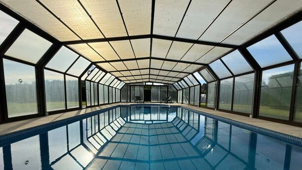 En swimmingpool med et glasloft, omgivet af store vinduer.